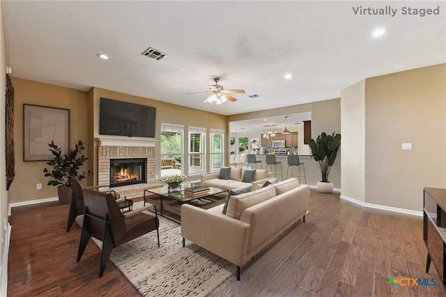 211 Gettysburg Loop, Elgin, TX 78621 - living room featuring a brick fireplace, visible vents, baseboards, ceiling fan, and dark wood-style floors