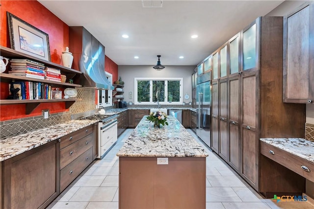 119 Stageline Dr, Kyle, TX 78640 - kitchen featuring high end appliances, a kitchen island, decorative backsplash, light stone counters, and light tile patterned floors