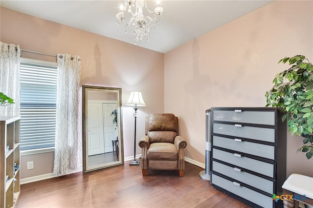 living area featuring an inviting chandelier, wood finished floors, baseboards, and a healthy amount of sunlight