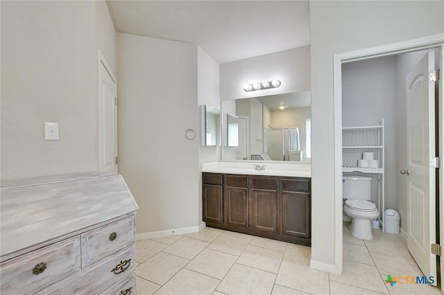 bathroom with tile patterned flooring, baseboards, toilet, a stall shower, and vanity