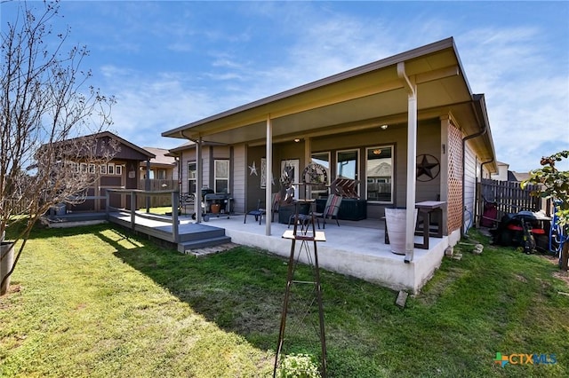 rear view of property featuring a deck, a patio, a yard, and fence