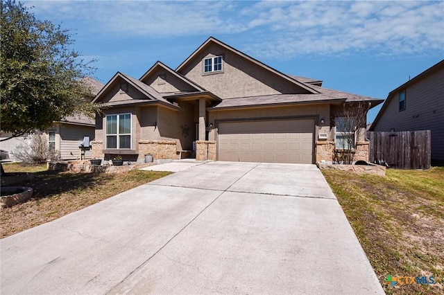 view of front of home with fence, stucco siding, driveway, stone siding, and an attached garage