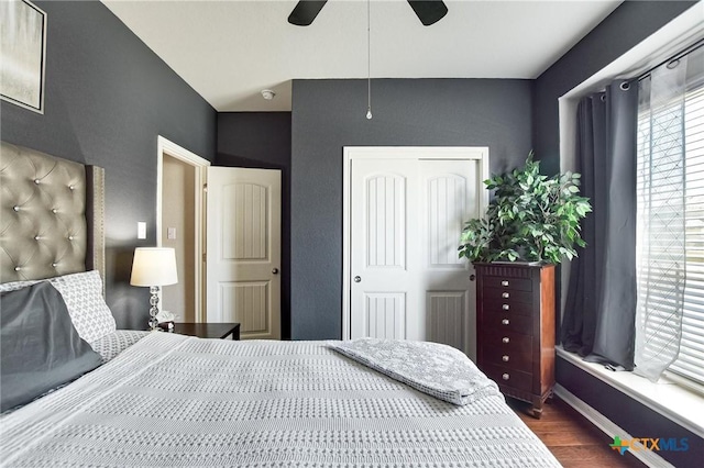 bedroom featuring a closet, baseboards, dark wood finished floors, and a ceiling fan