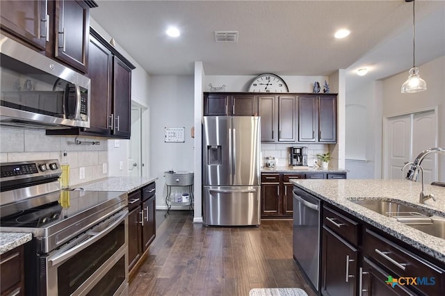 kitchen featuring visible vents, dark brown cabinetry, dark wood-style floors, stainless steel appliances, and a sink