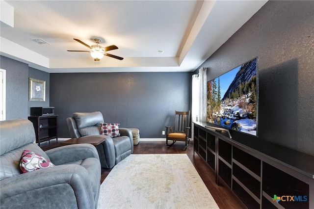 cinema featuring visible vents, baseboards, ceiling fan, dark wood finished floors, and a textured wall