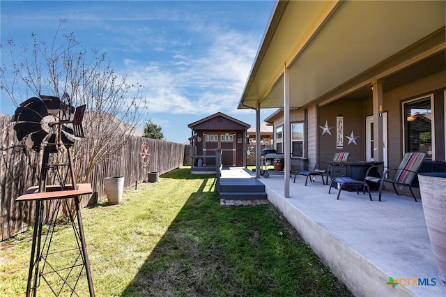 view of yard featuring an outbuilding, a storage shed, a fenced backyard, and a patio area