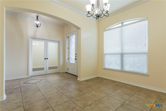 tiled foyer entrance with a chandelier, french doors, and crown molding