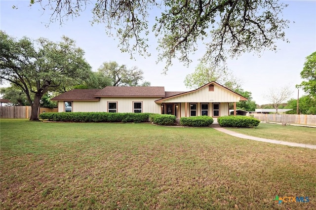 rear view of house featuring fence and a yard