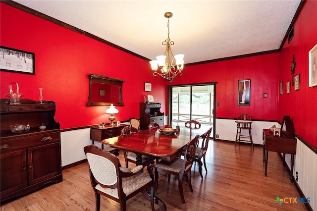 dining space with light wood-style flooring, a notable chandelier, and crown molding