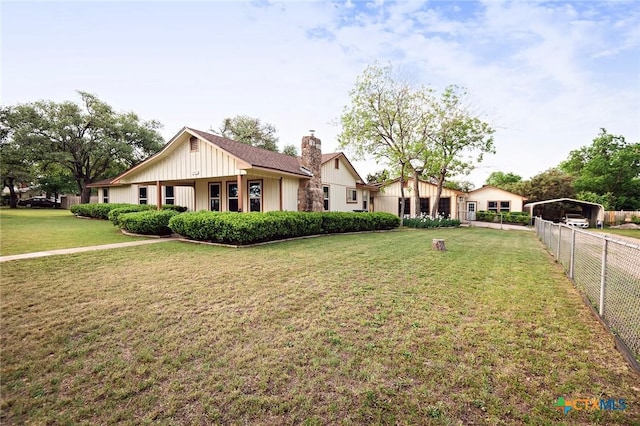 ranch-style home featuring a chimney, a front lawn, a carport, board and batten siding, and fence