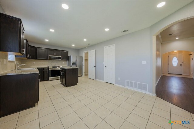3907 Llano Estacado Ct, Killeen, TX 76549 - kitchen with appliances with stainless steel finishes, light countertops, arched walkways, a center island, and tasteful backsplash