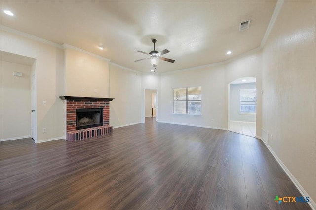 3907 Llano Estacado Ct, Killeen, TX 76549 - unfurnished living room featuring ceiling fan, crown molding, dark wood finished floors, a fireplace, and arched walkways