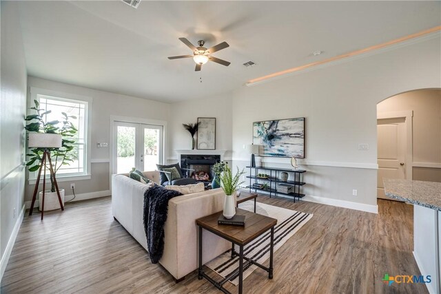 166 Lost Maples Way, Marion, TX 78124 - living area with arched walkways, a stone fireplace, ceiling fan, wood finished floors, and baseboards
