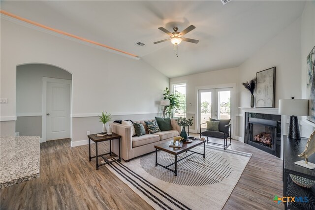 living room with french doors, vaulted ceiling, ceiling fan, a tile fireplace, and hardwood / wood-style floors