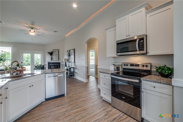 kitchen featuring light stone countertops, appliances with stainless steel finishes, sink, light hardwood / wood-style floors, and white cabinetry