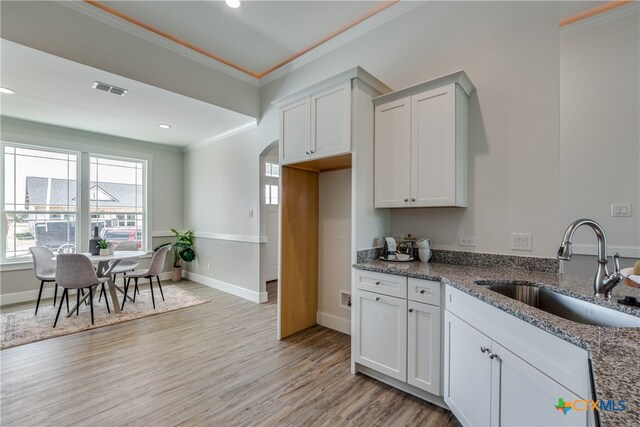 kitchen with light wood-type flooring, white cabinetry, sink, and dark stone counters