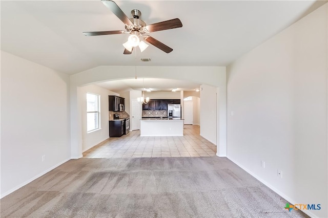 5402 Waterbank Ln, Killeen, TX 76543 - unfurnished living room with arched walkways, light colored carpet, a chandelier, a ceiling fan, and baseboards