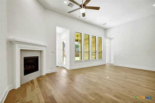 unfurnished living room featuring a fireplace, light wood-type flooring, and ceiling fan