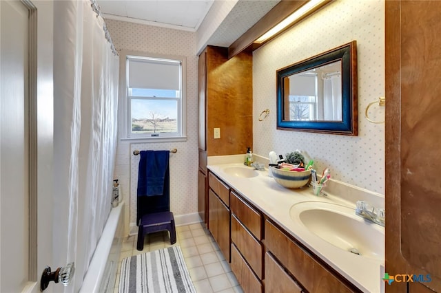 full bath with a sink, baseboards, double vanity, and wallpapered walls