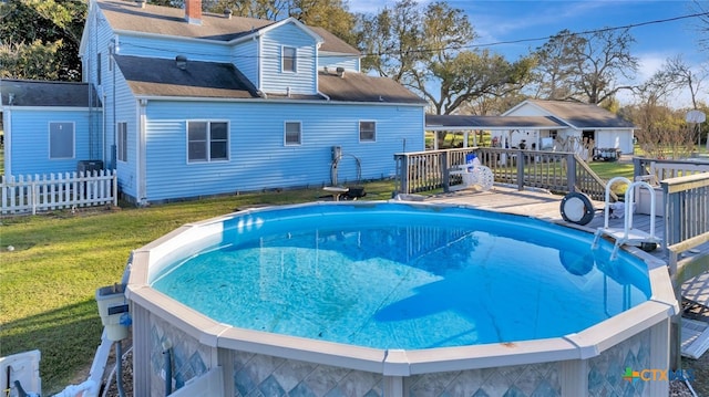 outdoor pool with a lawn, a deck, and fence