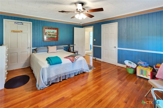 bedroom with a ceiling fan, wood finished floors, and ornamental molding