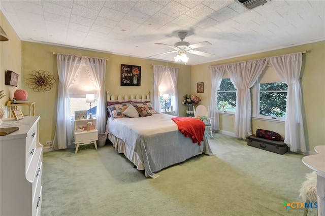 bedroom with visible vents, light colored carpet, ceiling fan, and crown molding