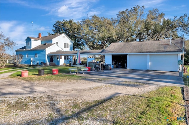 view of front of property featuring dirt driveway, a chimney, an outdoor structure, and a front yard