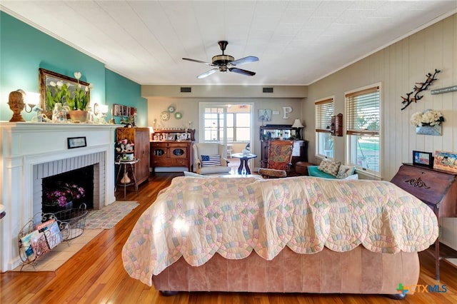 bedroom with visible vents, wood finished floors, a fireplace, and crown molding