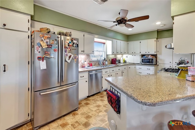 kitchen with appliances with stainless steel finishes, a peninsula, and white cabinetry