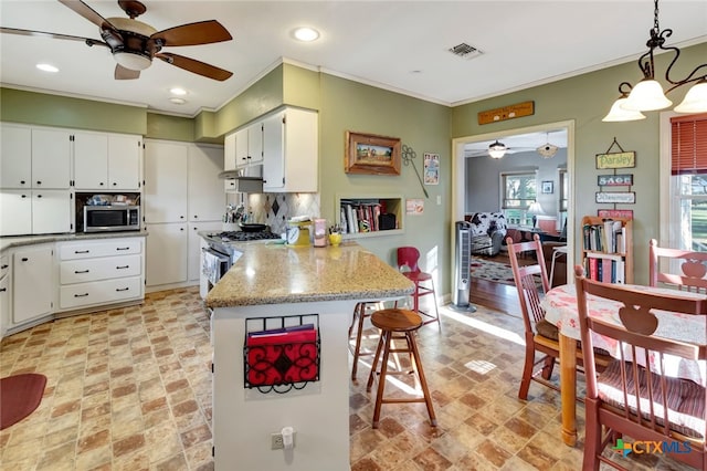 kitchen with a kitchen bar, ornamental molding, white cabinetry, appliances with stainless steel finishes, and a peninsula