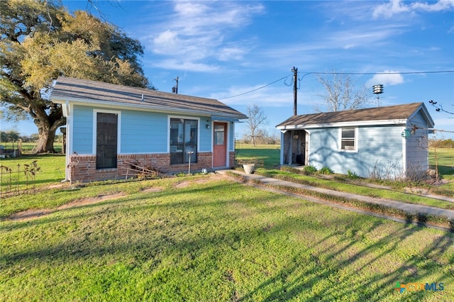 rear view of house with an outdoor structure, a lawn, and brick siding