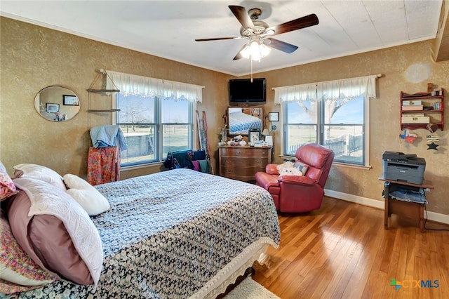 bedroom with hardwood / wood-style floors, crown molding, multiple windows, and a textured wall