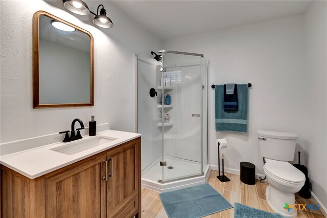 bathroom featuring toilet, vanity, wood-type flooring, and a shower with shower door