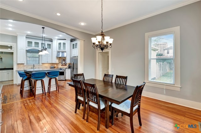 dining space with light wood-type flooring, a chandelier, and crown molding