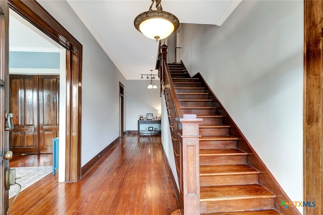 stairs featuring hardwood / wood-style flooring and crown molding