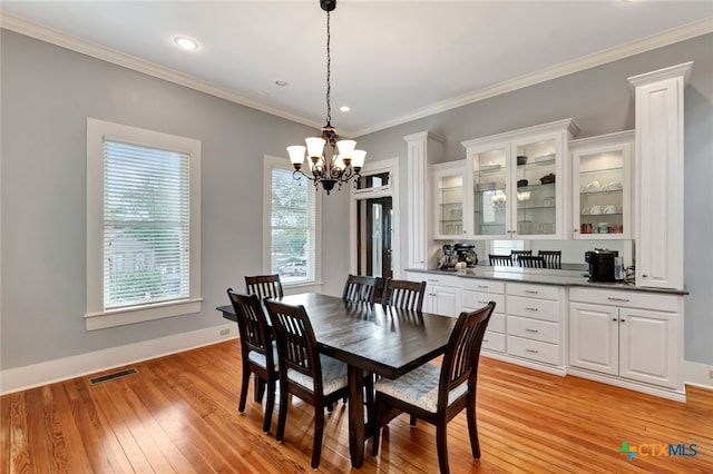 dining area featuring light hardwood / wood-style flooring, crown molding, and a notable chandelier