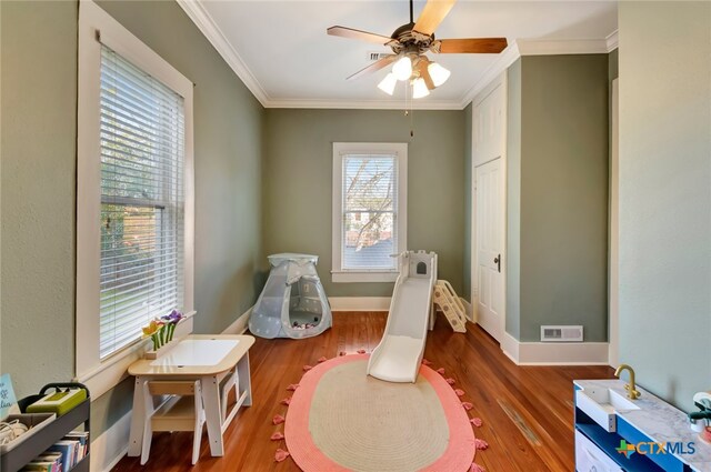 playroom with wood-type flooring, plenty of natural light, and ornamental molding