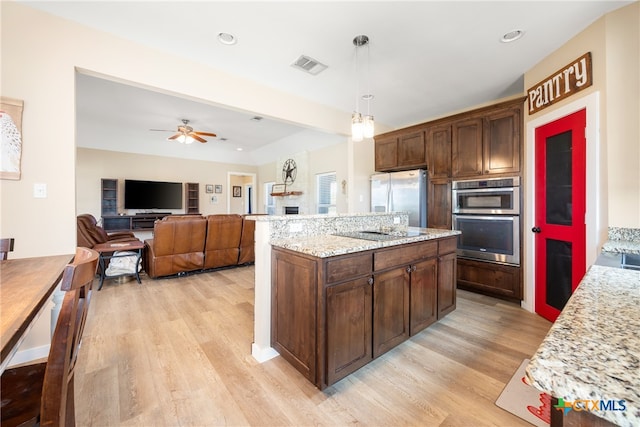 kitchen featuring light wood-type flooring, appliances with stainless steel finishes, decorative light fixtures, and ceiling fan