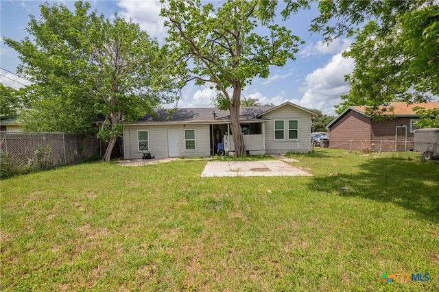 rear view of house with a fenced backyard, a patio area, and a yard