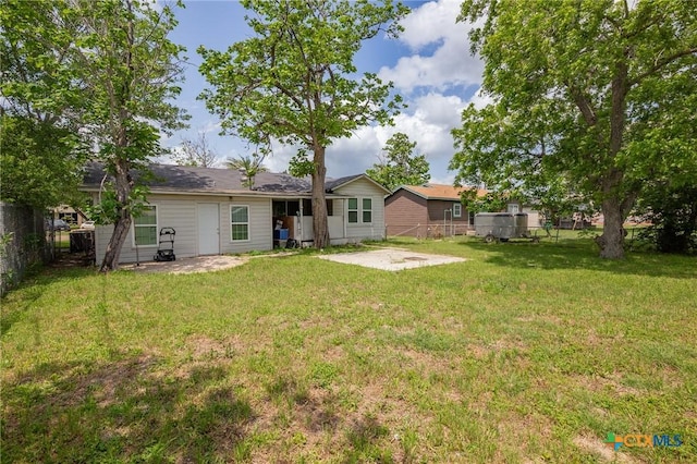 back of property featuring a lawn, fence, and a patio
