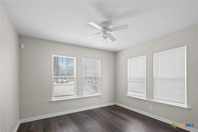 spare room featuring baseboards, dark wood finished floors, and ceiling fan