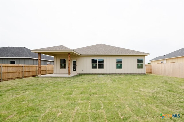 rear view of house featuring a lawn and a patio