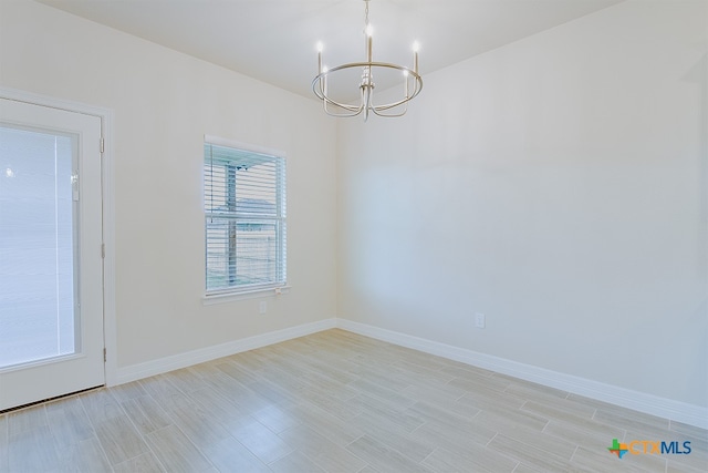 spare room featuring an inviting chandelier and light hardwood / wood-style flooring