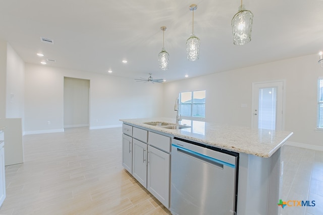 kitchen featuring a center island with sink, sink, stainless steel dishwasher, light stone countertops, and pendant lighting