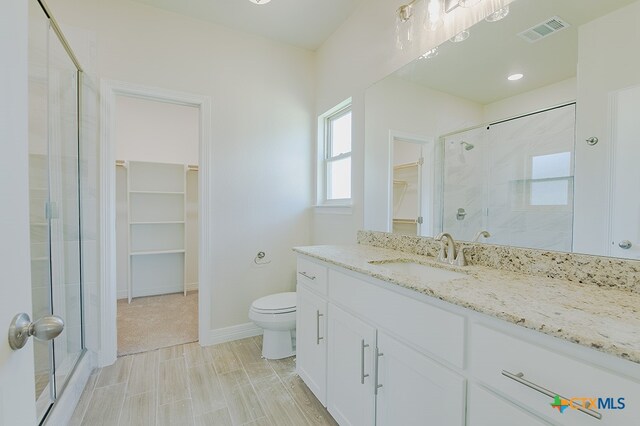 bathroom with walk in shower, vanity, and toilet