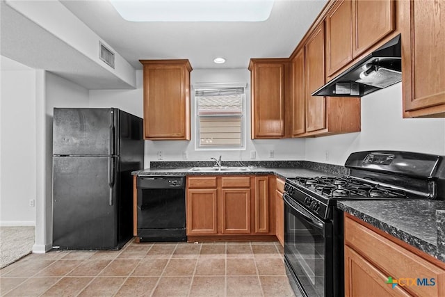 kitchen with a sink, brown cabinetry, under cabinet range hood, visible vents, and black appliances