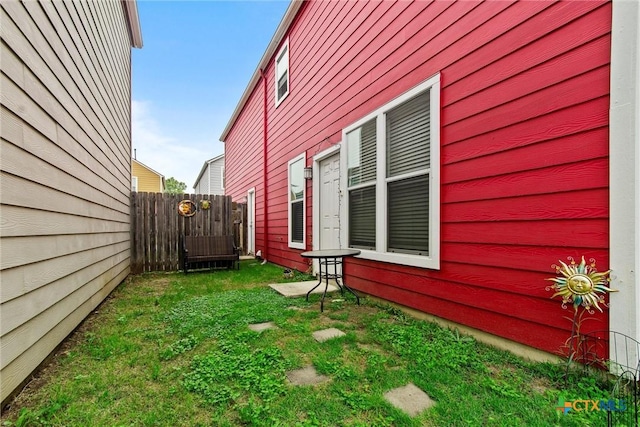 view of home's exterior featuring fence and a lawn