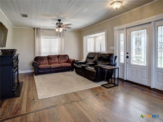 living room featuring ceiling fan, dark wood-style flooring, visible vents, baseboards, and crown molding