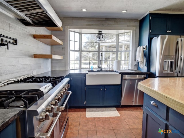 kitchen with stainless steel appliances, dark countertops, exhaust hood, and blue cabinets