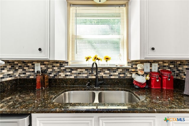 kitchen with backsplash, dark stone counters, white cabinets, and a sink